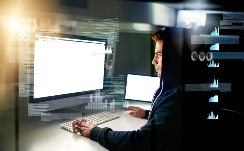 Persona frente a computadora con código en la pantalla en busca de errores de Software